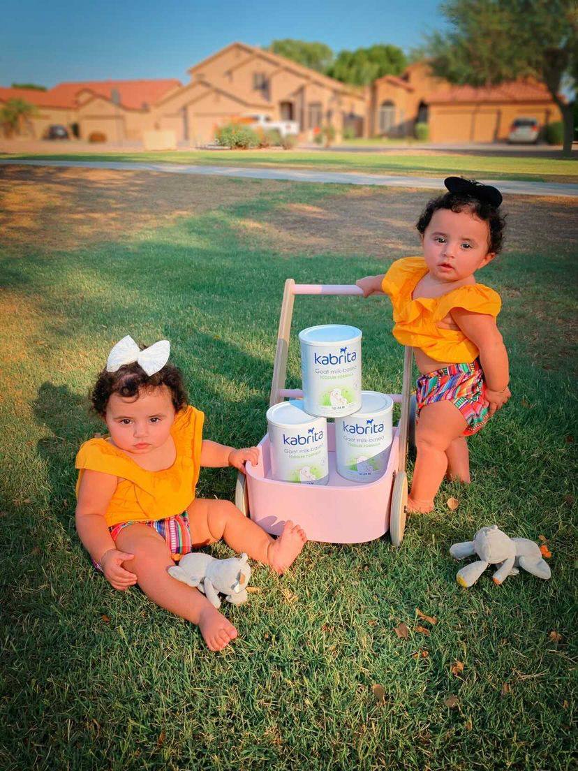 Twins standing outside at sunset with a baby cart carrying Kabrita's Goat Milk Formula