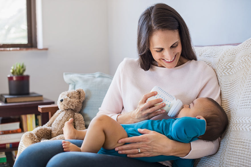 Smiling mother bottle feeding her baby