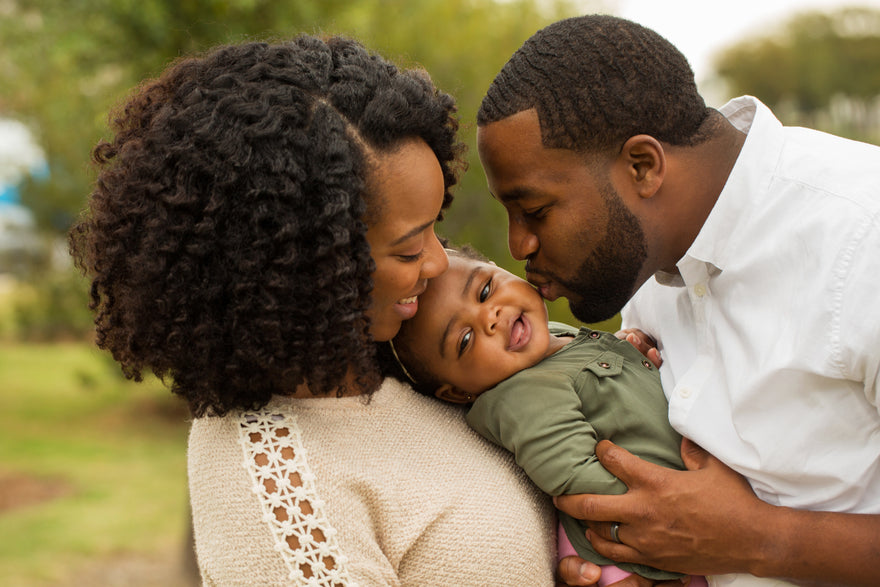 Happy family hugging and kissing toddler while enjoying the outdoors