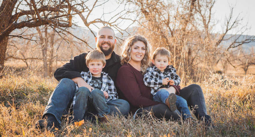 Happy family of four sitting in a sunny field outside in the fall.