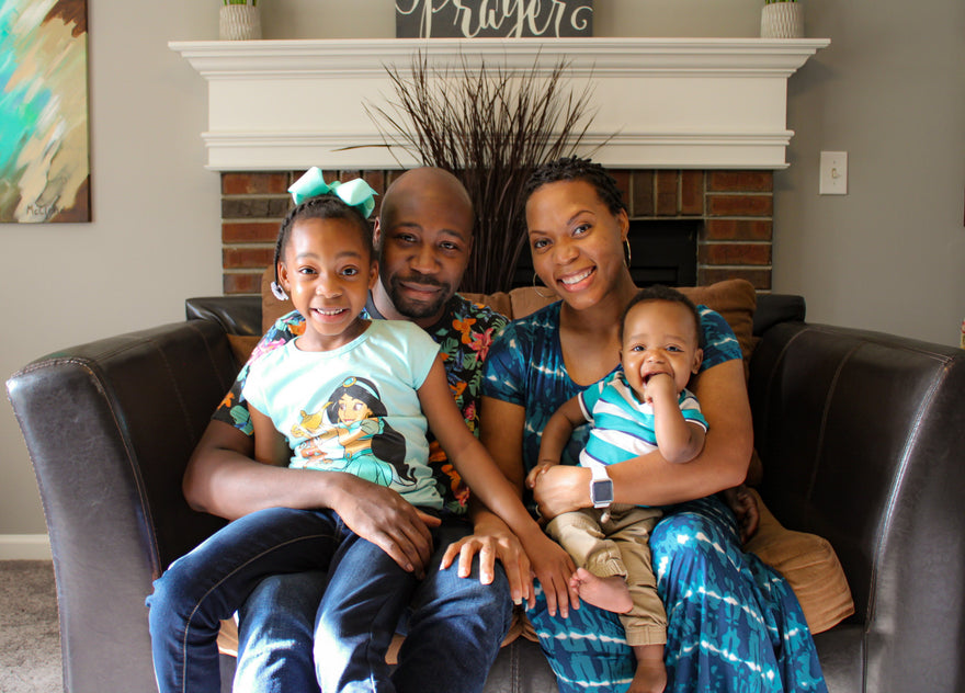Happy family of four smiling and sitting together on a couch.