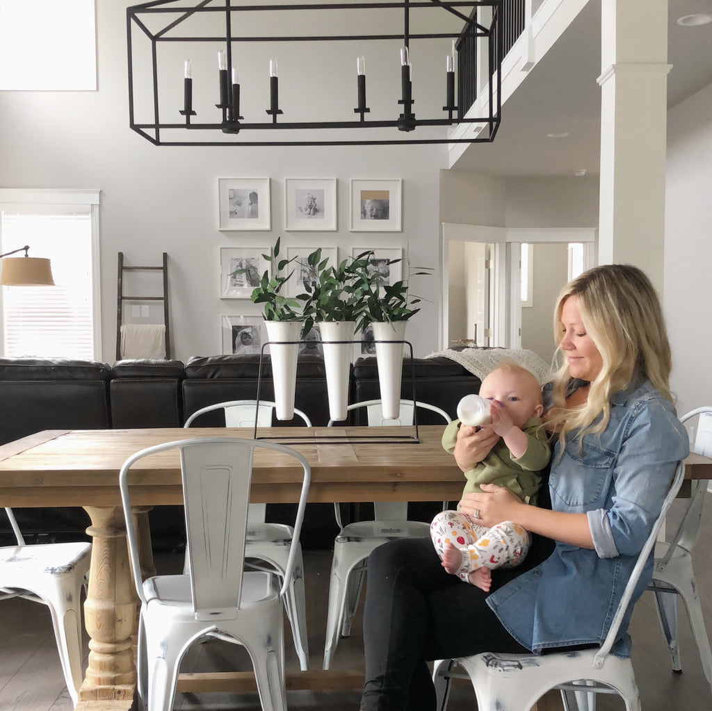 Mom bottle feeding her daughter at dining room table