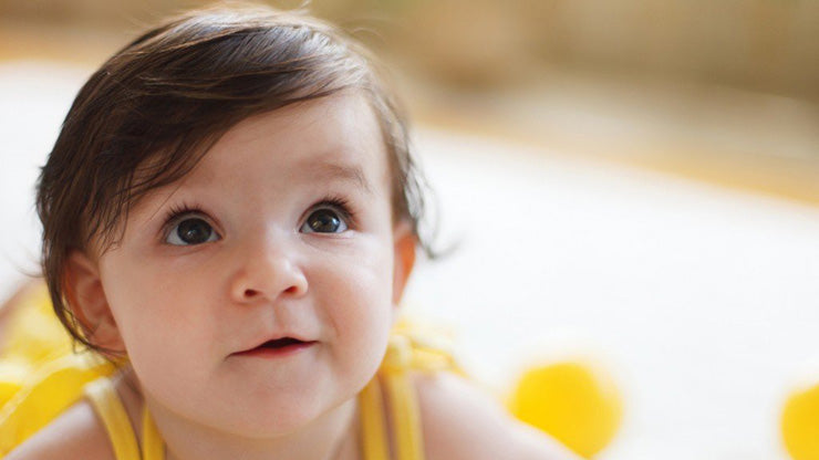 Smiling brown haired toddler looking up with delight